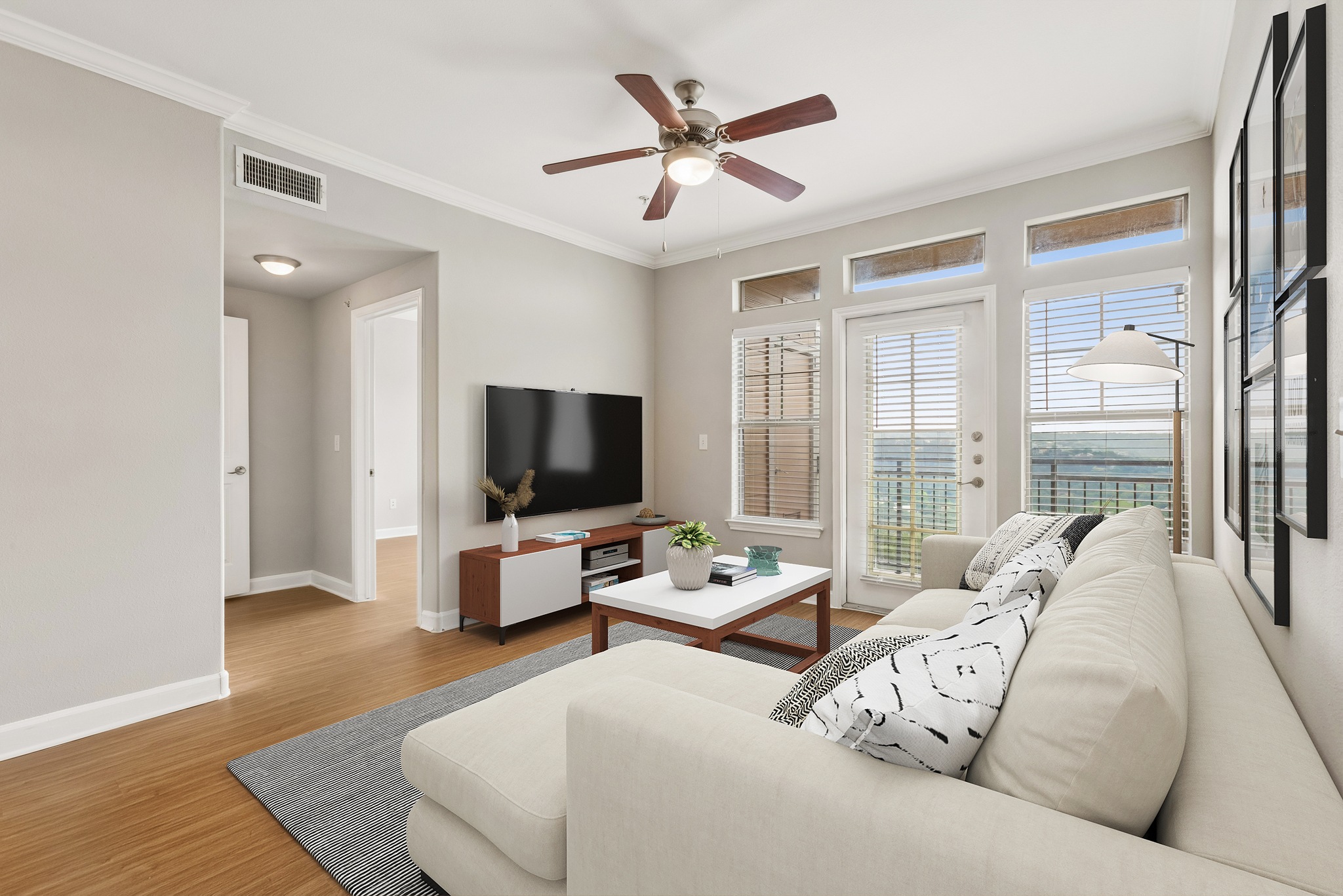 A living room with a couch, a television, and a ceiling fan.
